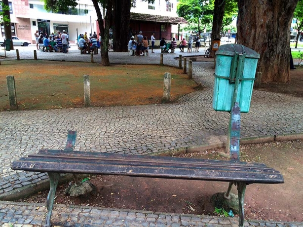 Um dos bancos em pior estado de conserva&ccedil;&atilde;o da pra&ccedil;a, e atr&aacute;s dele &aacute;rea que um dia foi gramada com uma lixeira velha