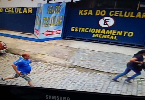 O homem mais gordo foi flagrado pelo policial tentando entrar em um prédio e a mulher à frente é, provavelmente, sua comparsa