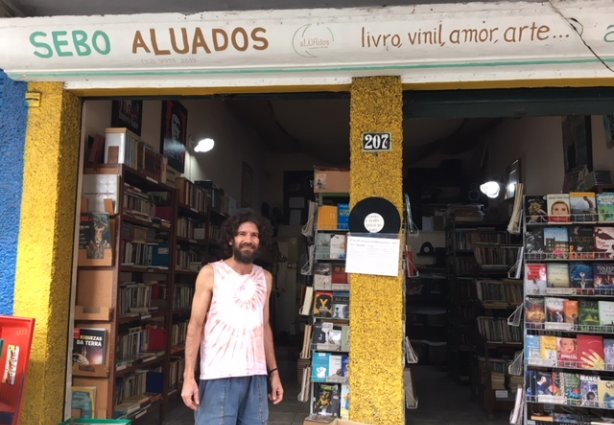 O professor mestre e proprietário do Sebo aLUAdos, Luciano de Andrade ao lado da banca de livros gratuitos