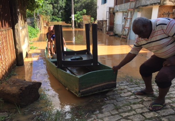 Morador próximo ao campo do Flamenguinho retira uma mesa de sua casa invadida pela água