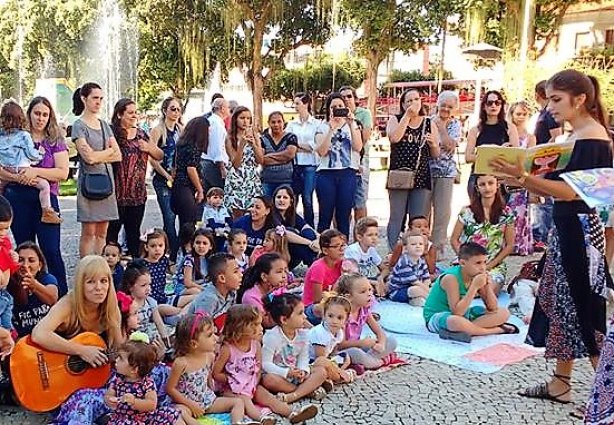 Juliana, ao violão, rodeada de crianças em um evento na Praça Santa Rita