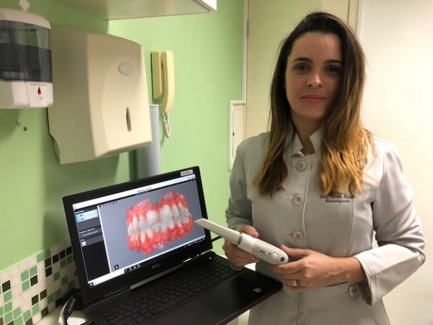 Aline Brum segura o aparelho de escaneamento intra oral colorido, a &uacute;ltima inova&ccedil;&atilde;o da cl&iacute;nica Faces Diagn&oacute;sticos